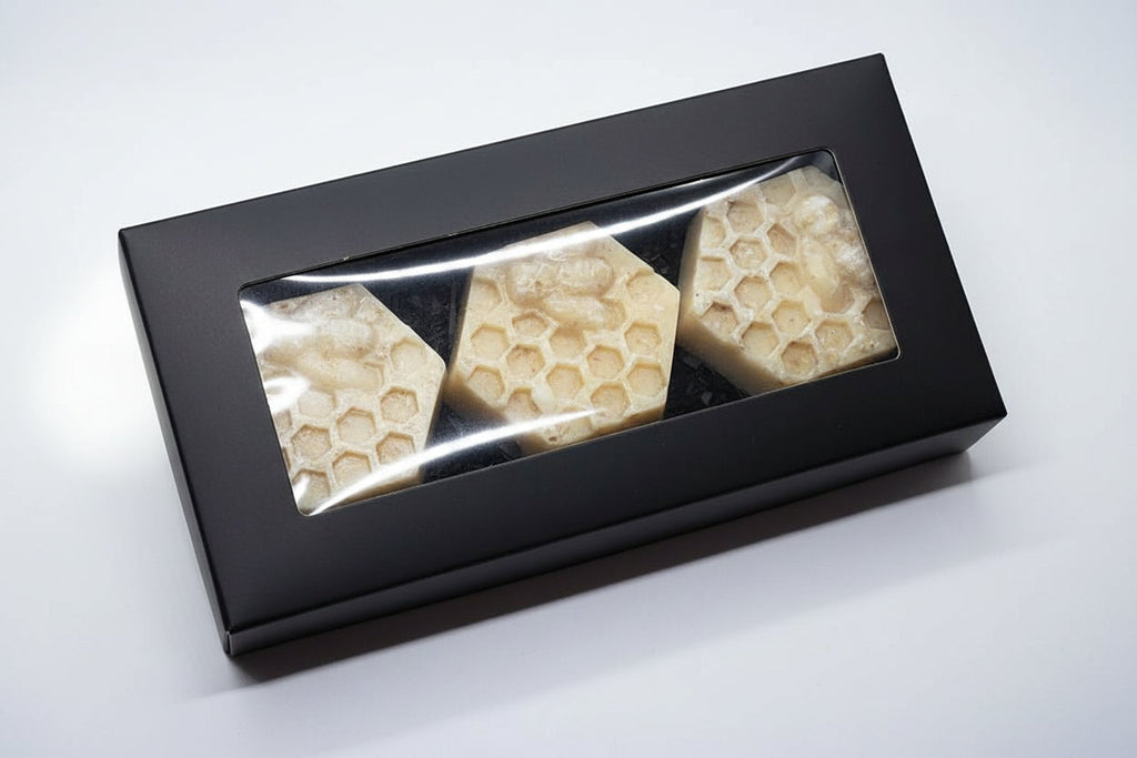 Three hexagonal honeycomb-shaped soaps in a black box on a white background